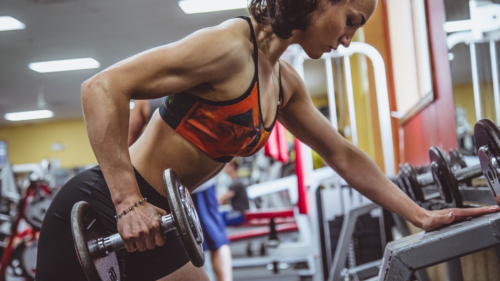 A person in workout clothes squatting with arms extended forward, focused on their depth and posture.