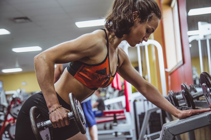 A person in workout clothes squatting with arms extended forward, focused on their depth and posture.