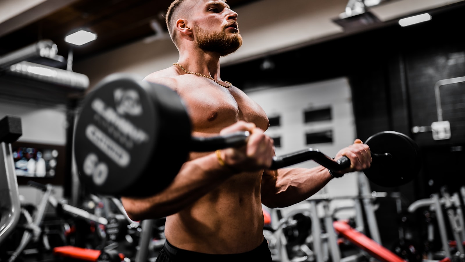 A beginner gripping a barbell on the gym floor, focused on setting up before a lift.