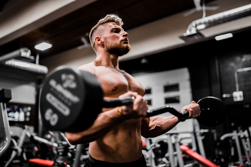 A beginner gripping a barbell on the gym floor, focused on setting up before a lift.